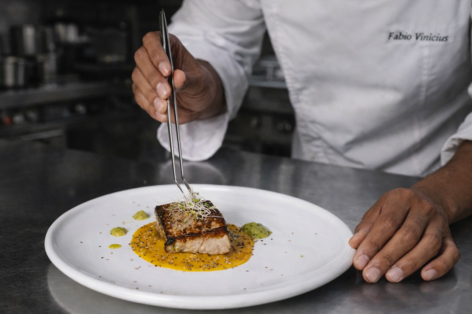 Chef finalizando peixe no prato com pinça
