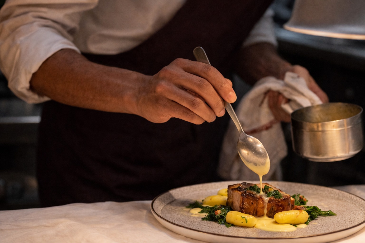Chef Fábio Vinicius finalizando prato com molho